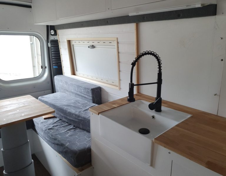 Innenraum eines Wohnmobils Minimalist Innenraum eines Wohnmobils mit Küchenzeile, Essbereich und Sitzecke.