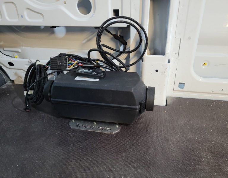 Heizung für Camper Ein schwarzes Heizgerät mit Kabeln, auf einem grauen Untergrund.
